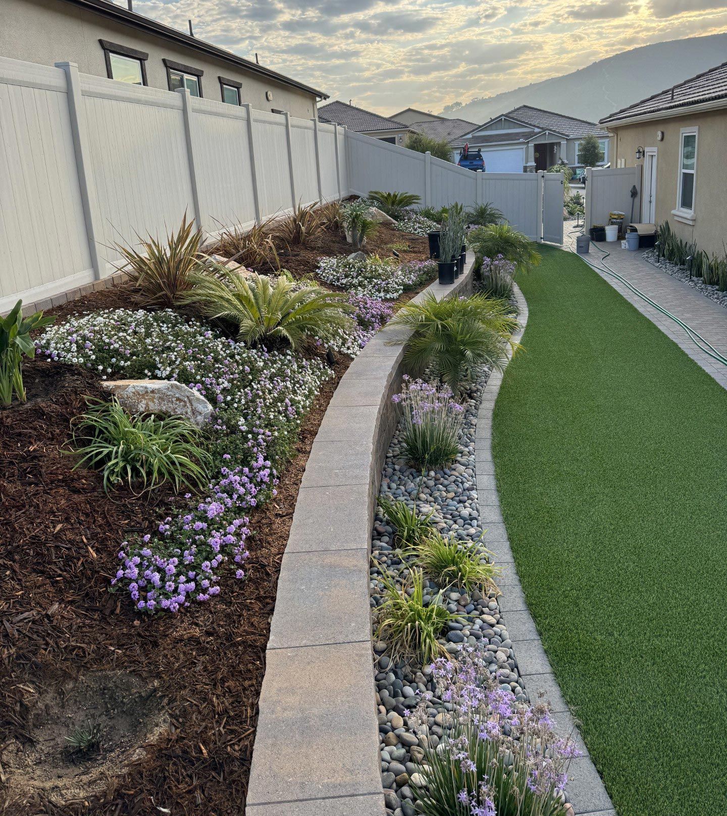 A garden with a brick walkway leading to a house.