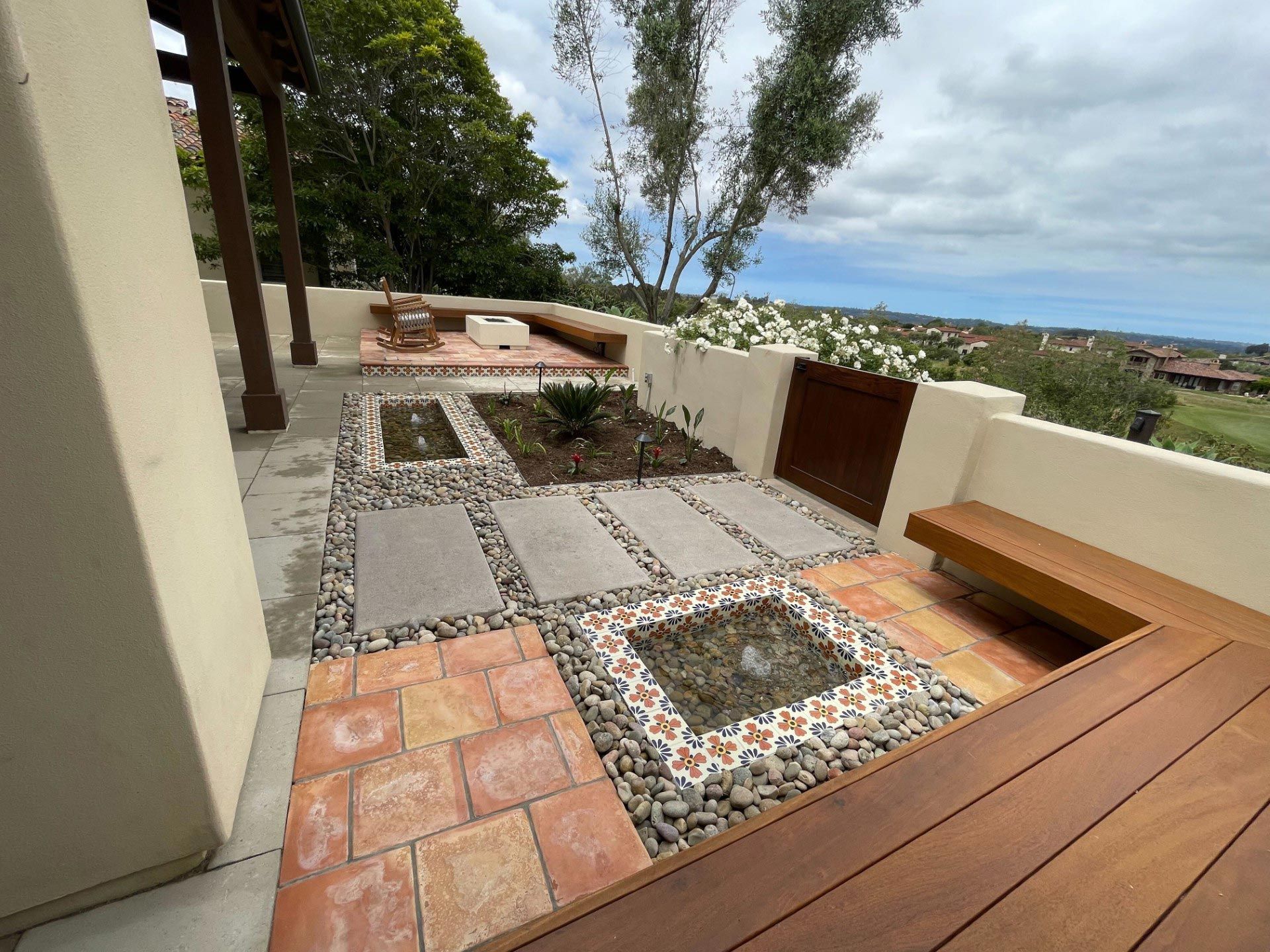 A wooden deck with a bench and a fountain in the middle of it.