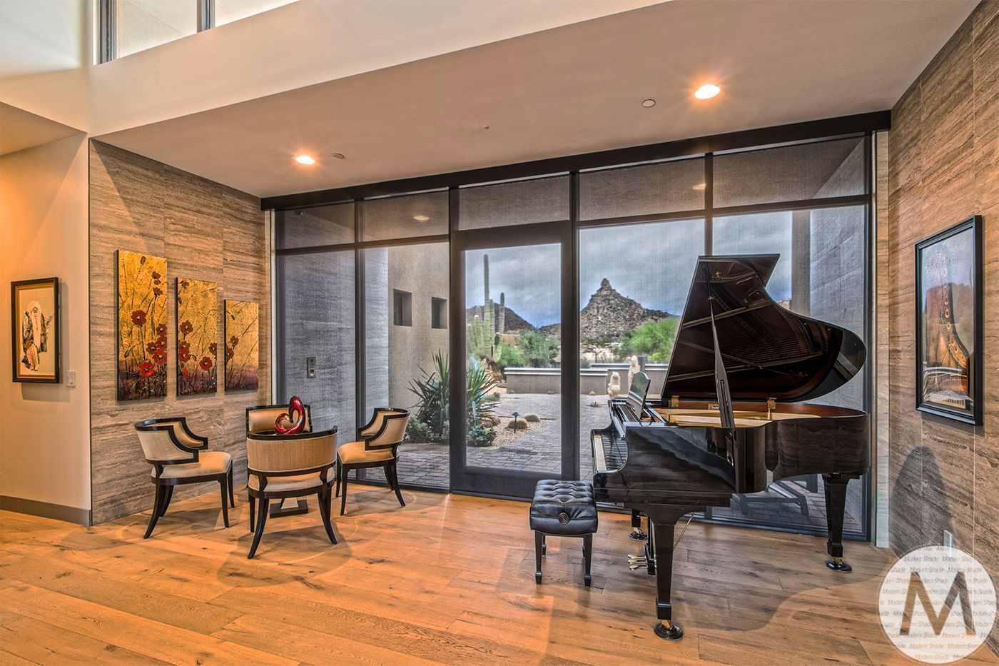 Modern living room with piano, seating, artwork, and glass doors opening to a patio view
