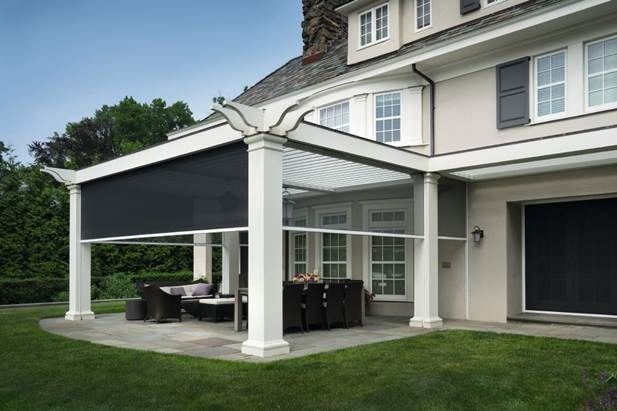 Covered patio beside a gray house with white columns, outdoor dining furniture, and green lawn
