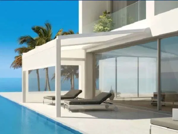 Modern white villa with infinity pool, lounge chairs, and glass walls by the ocean