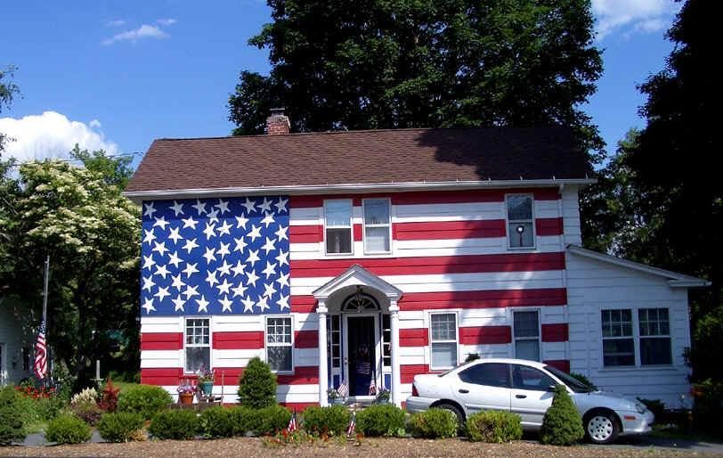 House painted like the U.S. flag with a white car parked in front