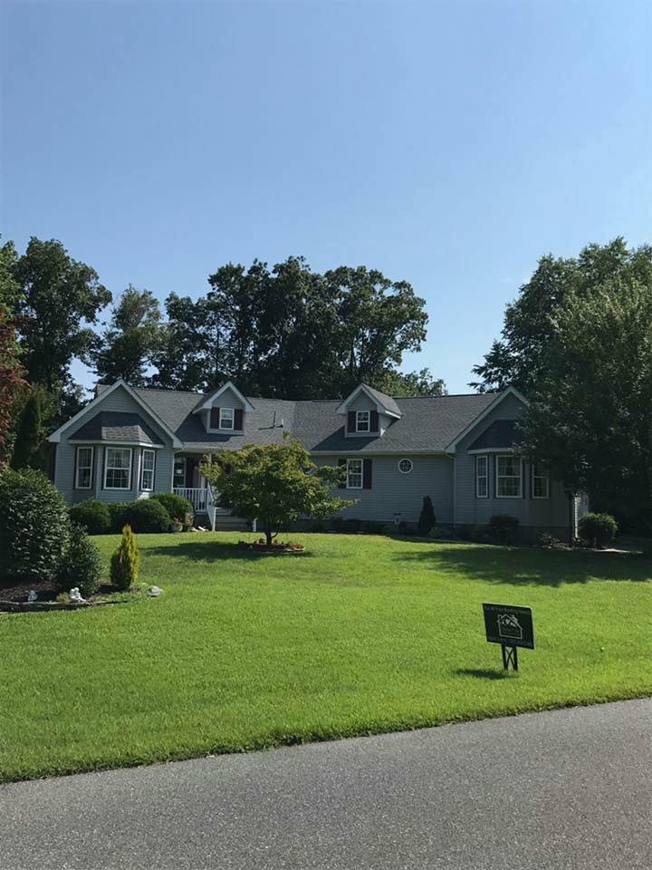 Gray house with dormer windows on a green lawn under a blue sky