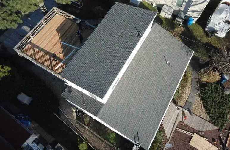 Aerial view of a house with a gray roof and a small wooden deck beside it.
