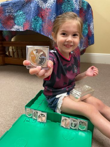Cute kid holding silver coins and bars