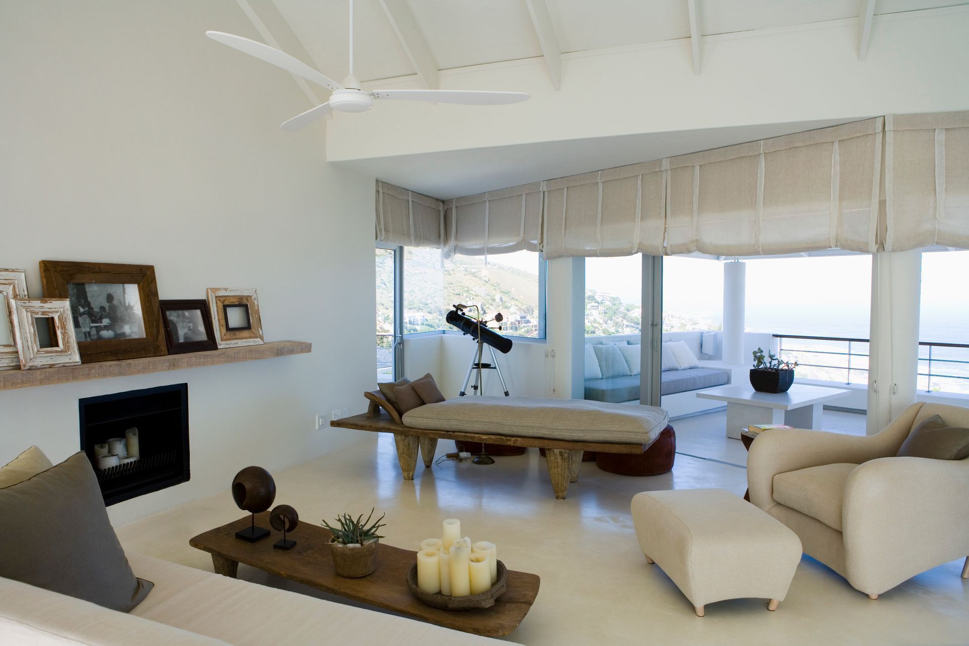 Modern white living room with fireplace, sectional sofa, coffee table, and ocean-view windows