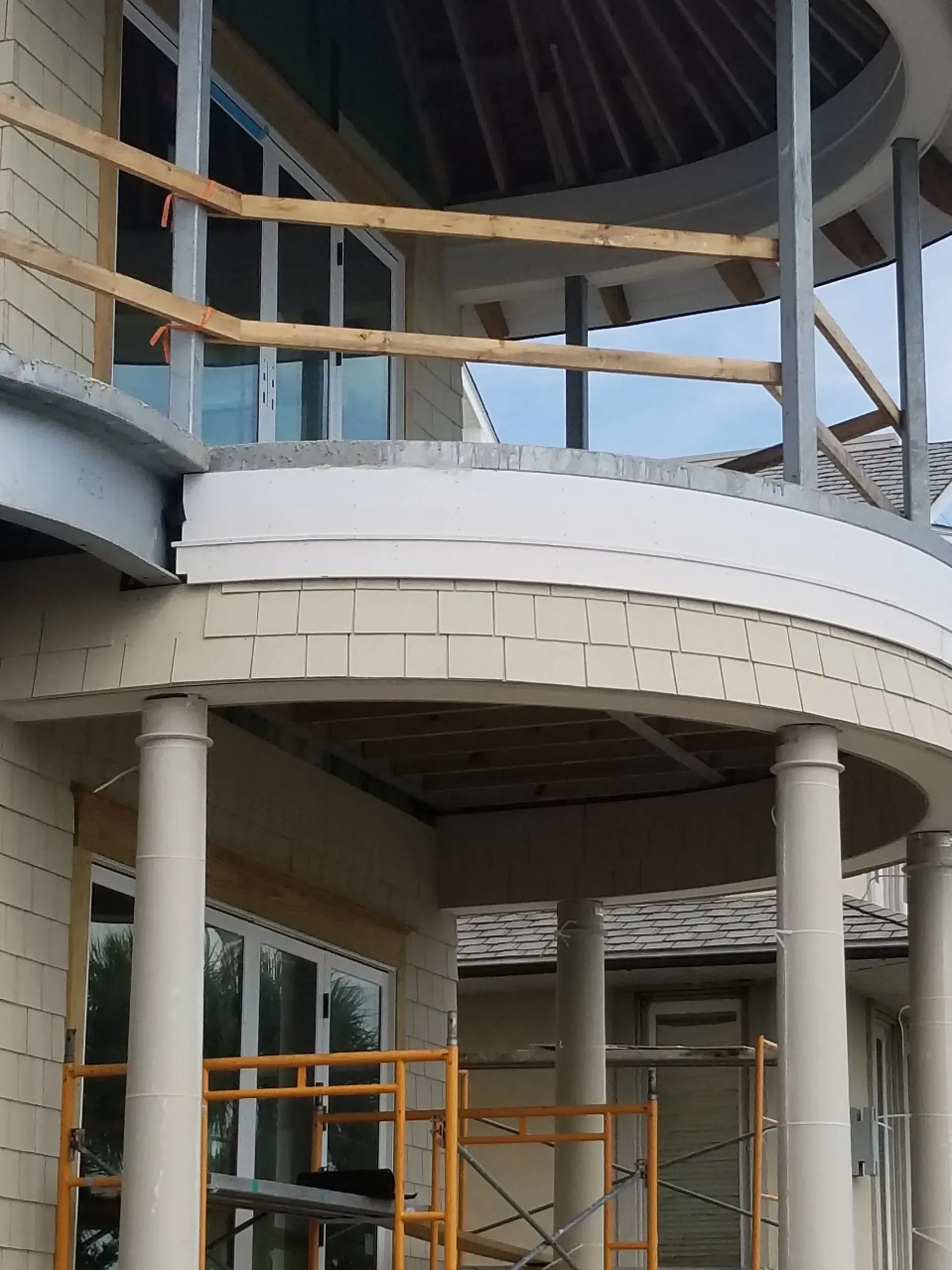 Curved building facade with columns, balconies, and scaffolding under construction
