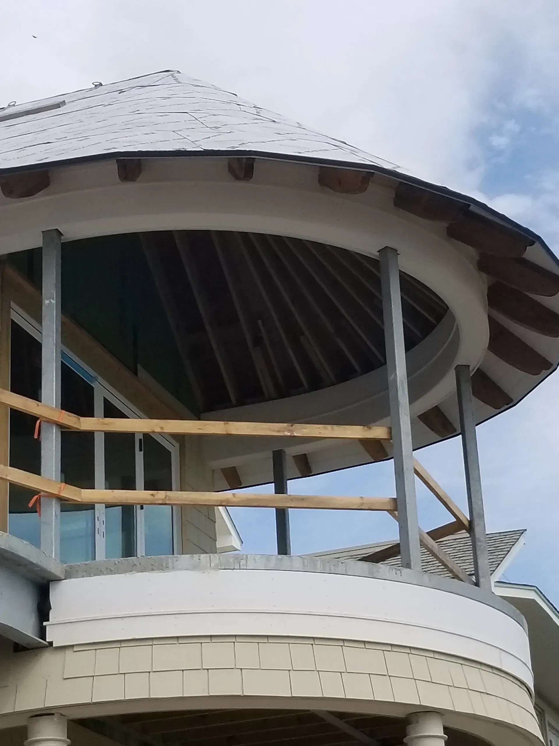 Round pavilion with a gray roof and white railings against a partly cloudy sky