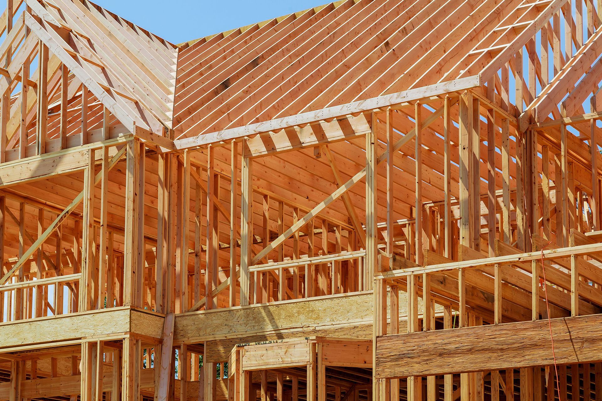 Wood-framed house under construction with exposed roof trusses and walls