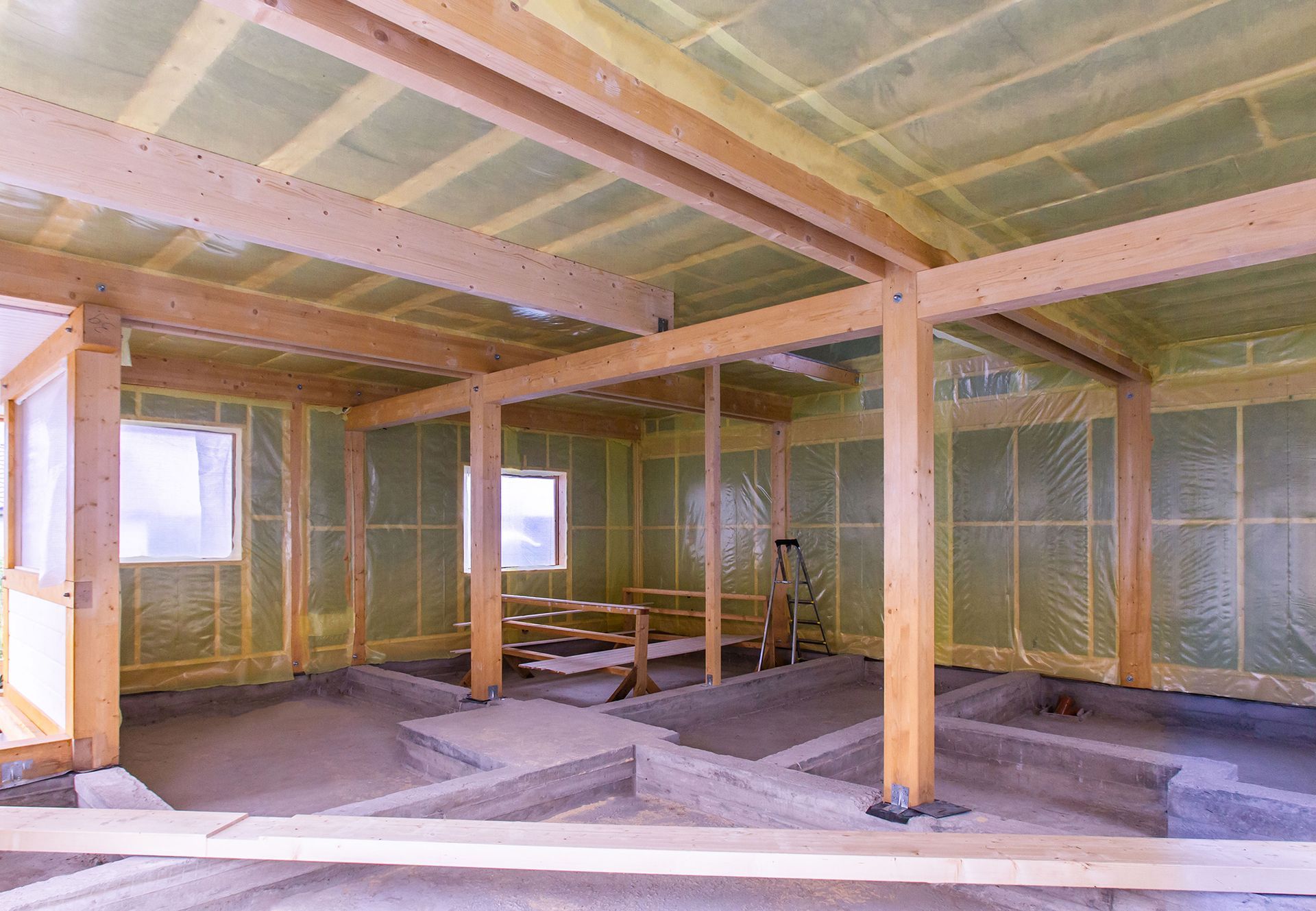Unfinished interior with exposed wooden beams, insulation, and scattered construction materials.