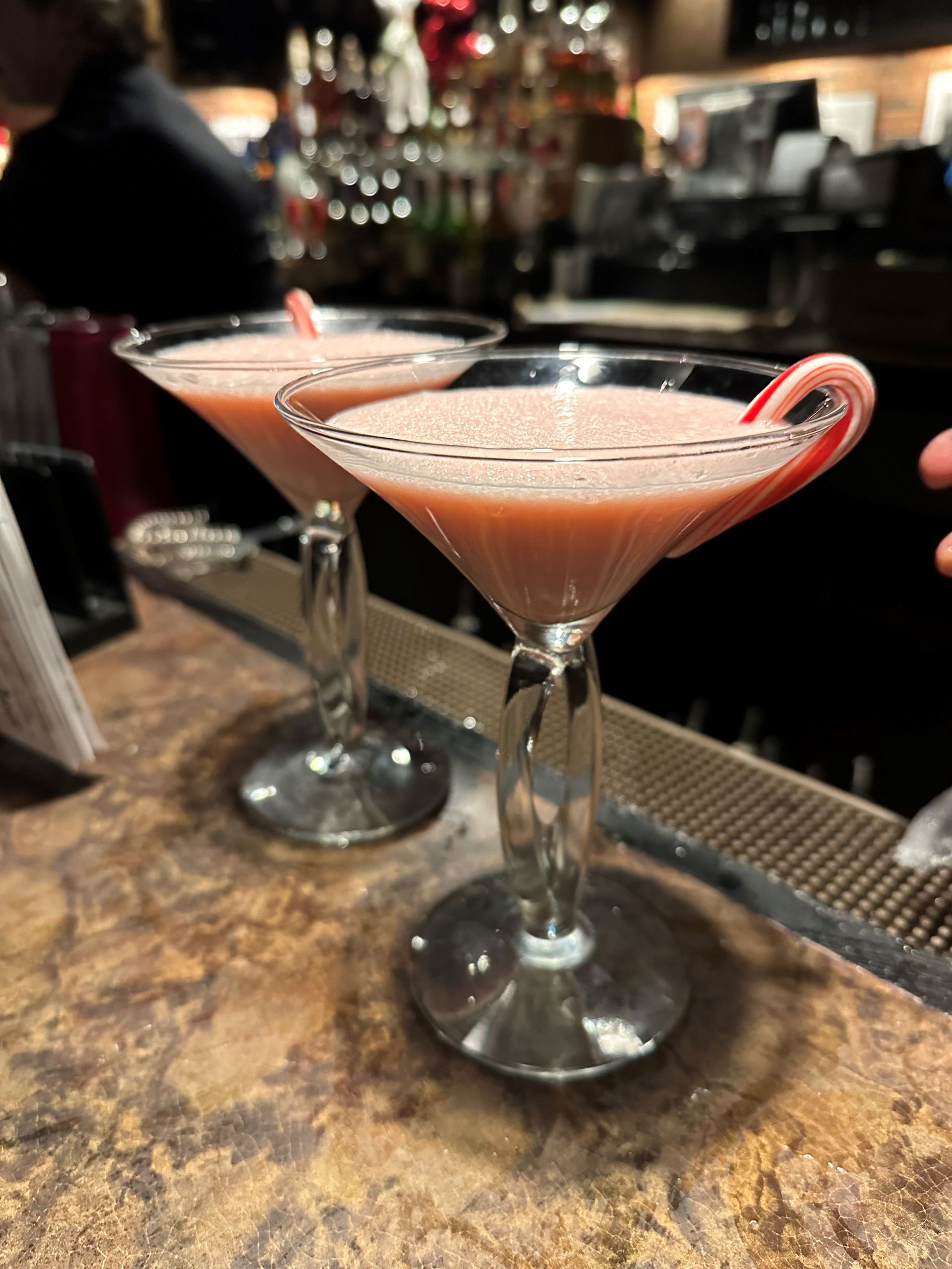 two martini glasses with a candy cane in them