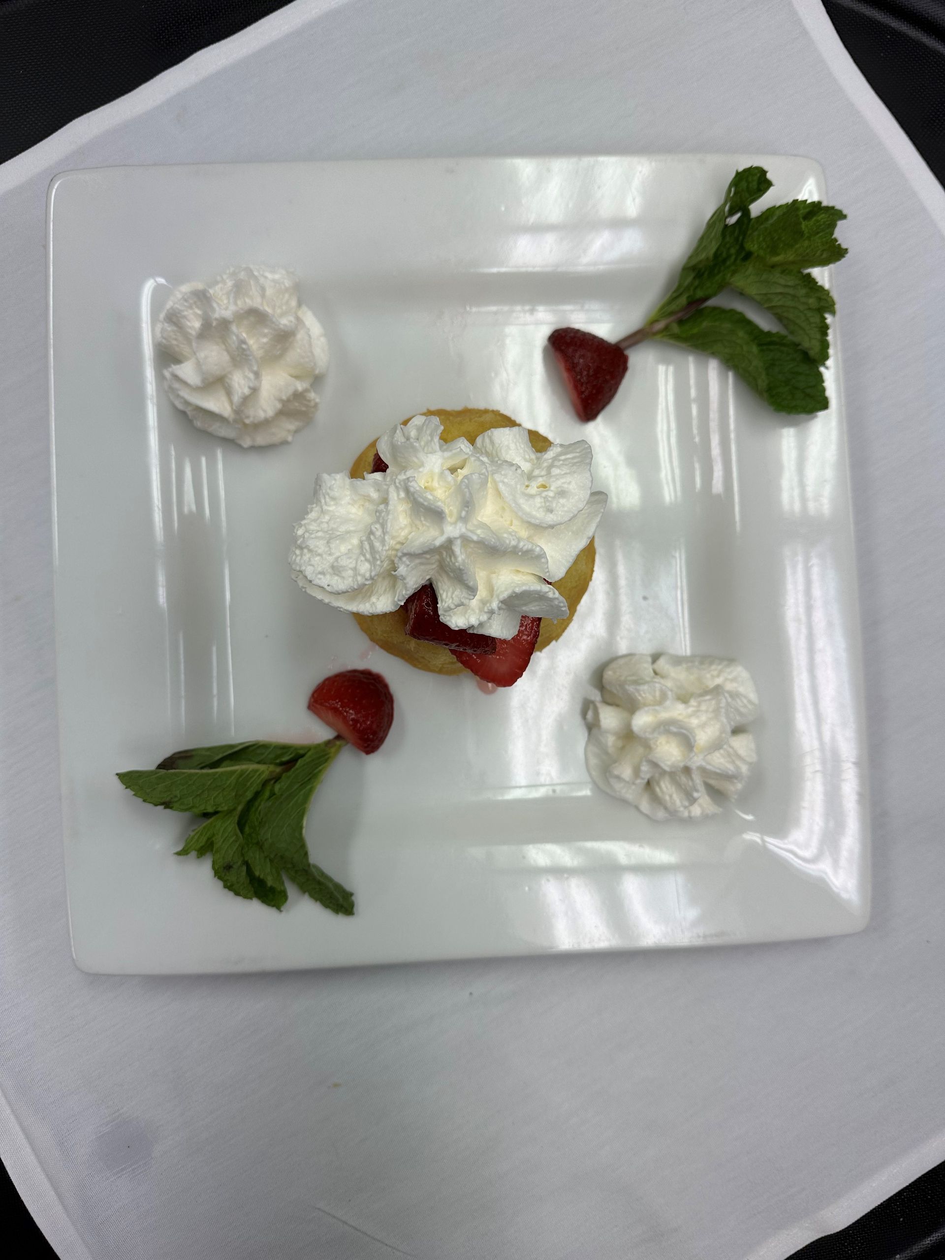 A dessert with whipped cream and strawberries on a white plate