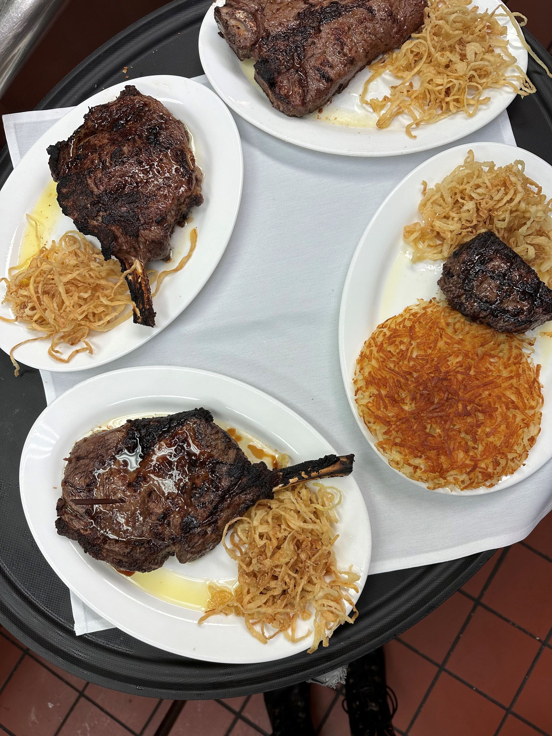 Four plates of food are on a tray on a table.