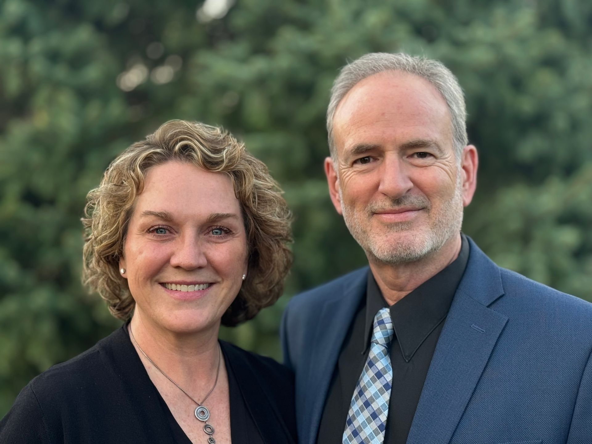 A man and a woman are posing for a picture in the grass.