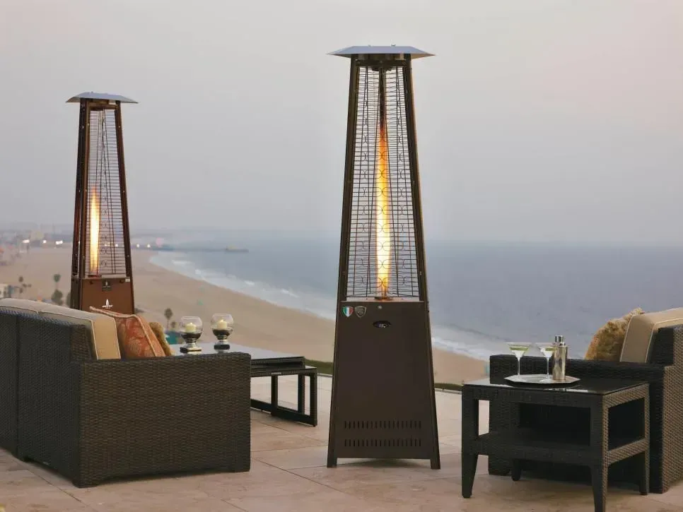 Beachside patio seating with tall heaters overlooking the ocean at dusk