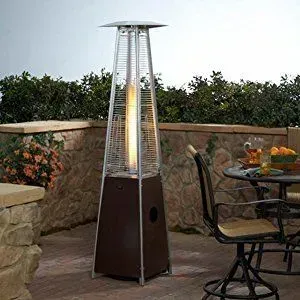 Patio heater beside a stone wall on an outdoor terrace with a table and chairs