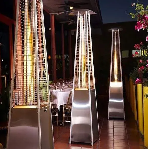 Outdoor patio with tall silver pyramid patio heaters beside a dining area at night