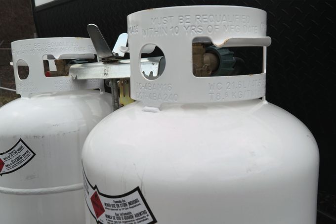 Two white propane tanks with metal collars, stacked close together.