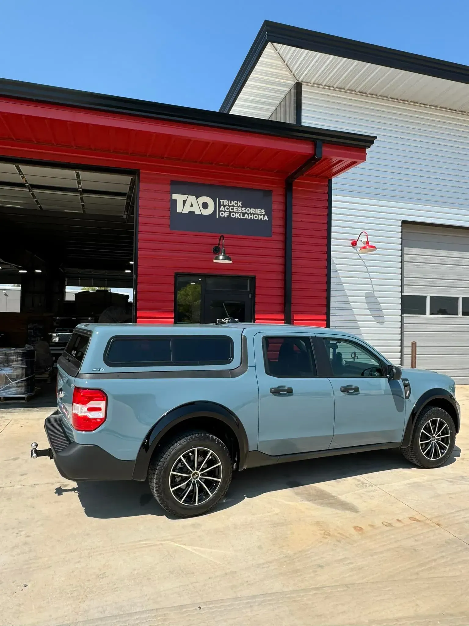 Blue SUV parked outside a modern auto shop with a red awning and open service bay.