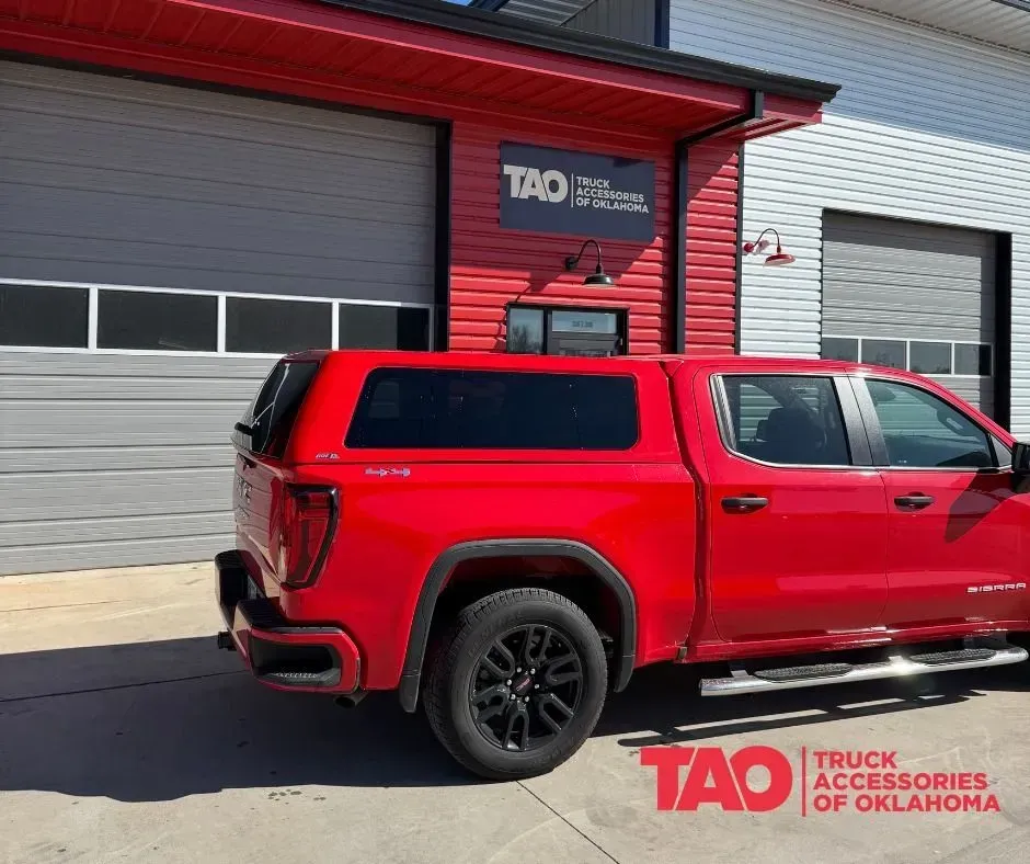 Red pickup truck parked outside a TAO Truck Accessories of Oklahoma shop.