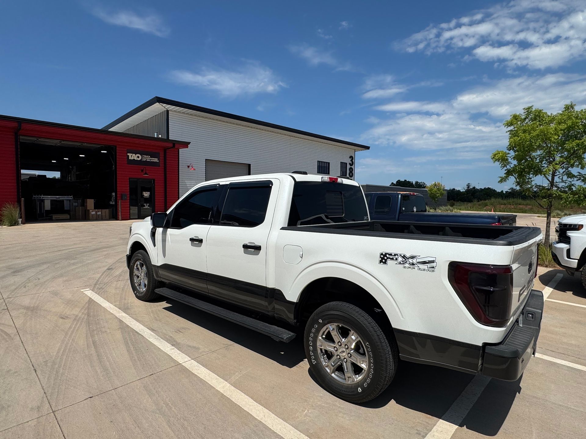 White pickup truck parked outside a red building on a sunny day