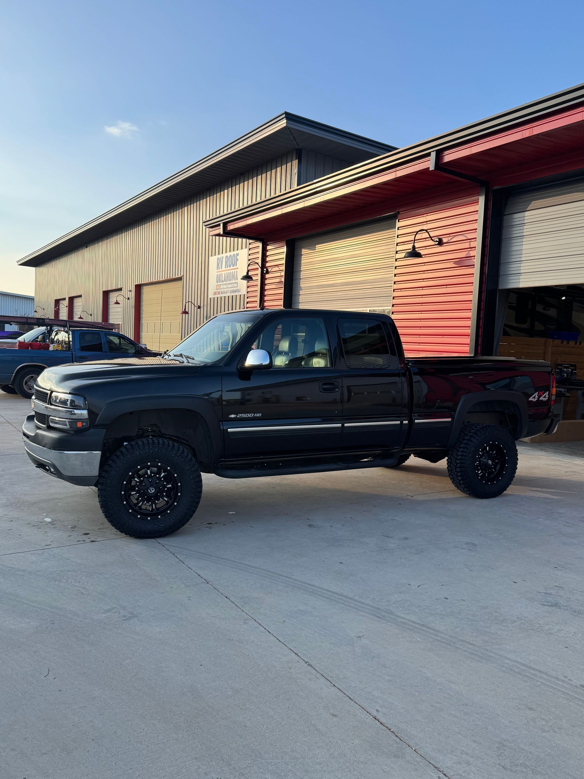Black pickup truck parked beside a warehouse on a concrete lot in daylight