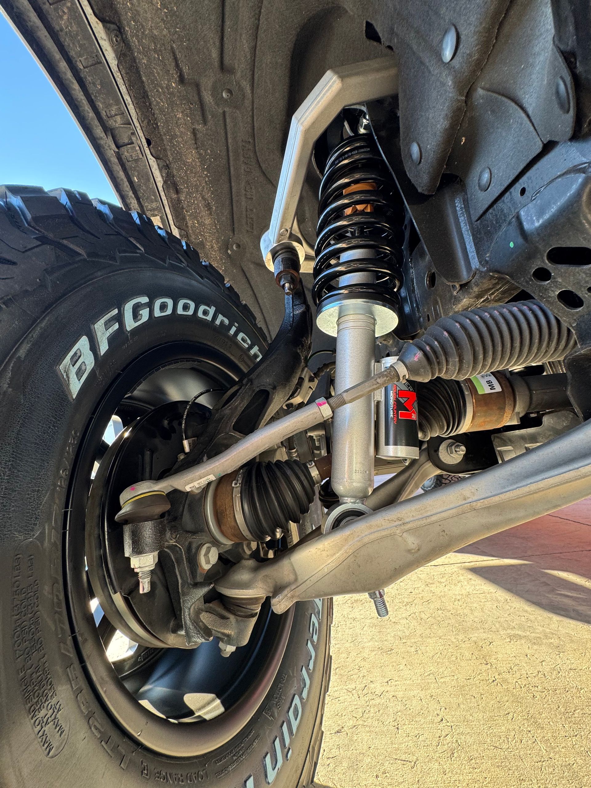 Close-up of a truck’s front suspension and wheel with BFGoodrich tire on rough terrain