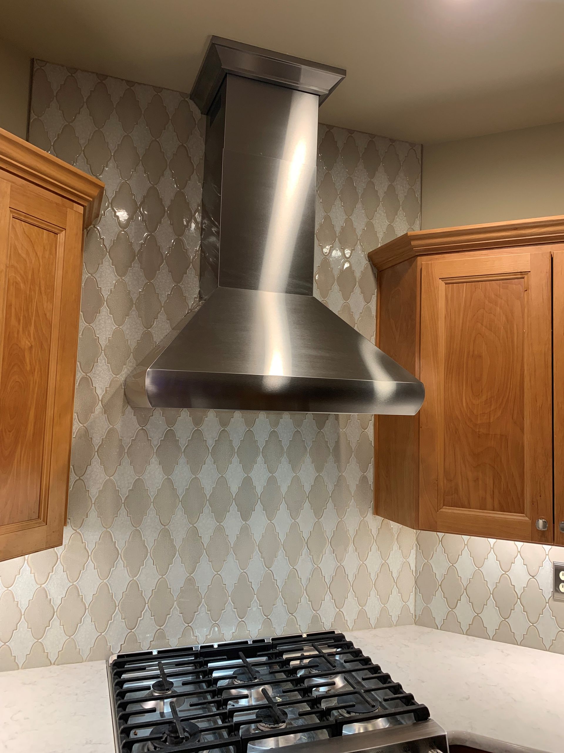 A kitchen with a stove top oven and a stainless steel hood.