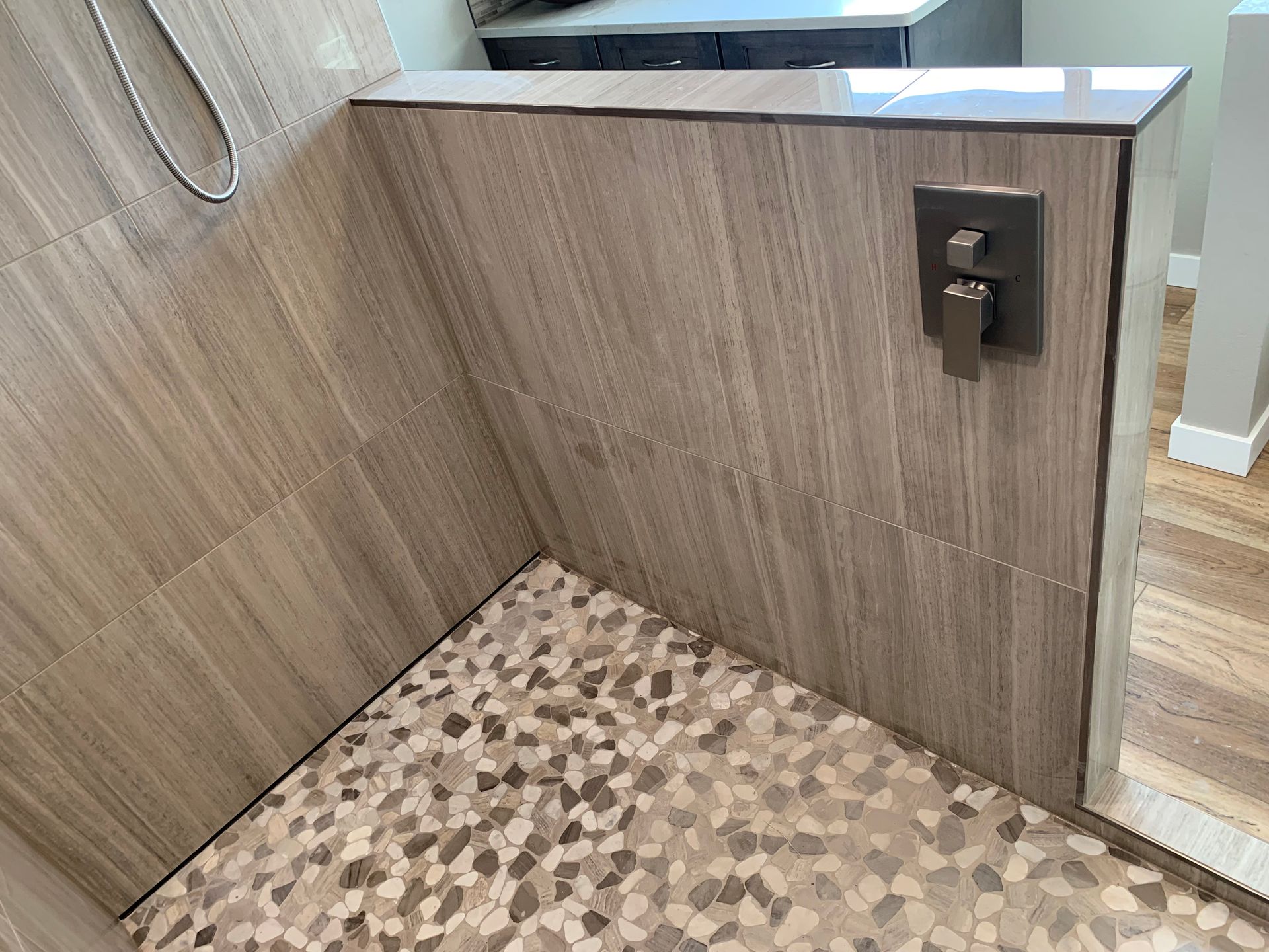 A shower with a tiled floor and a wooden wall.