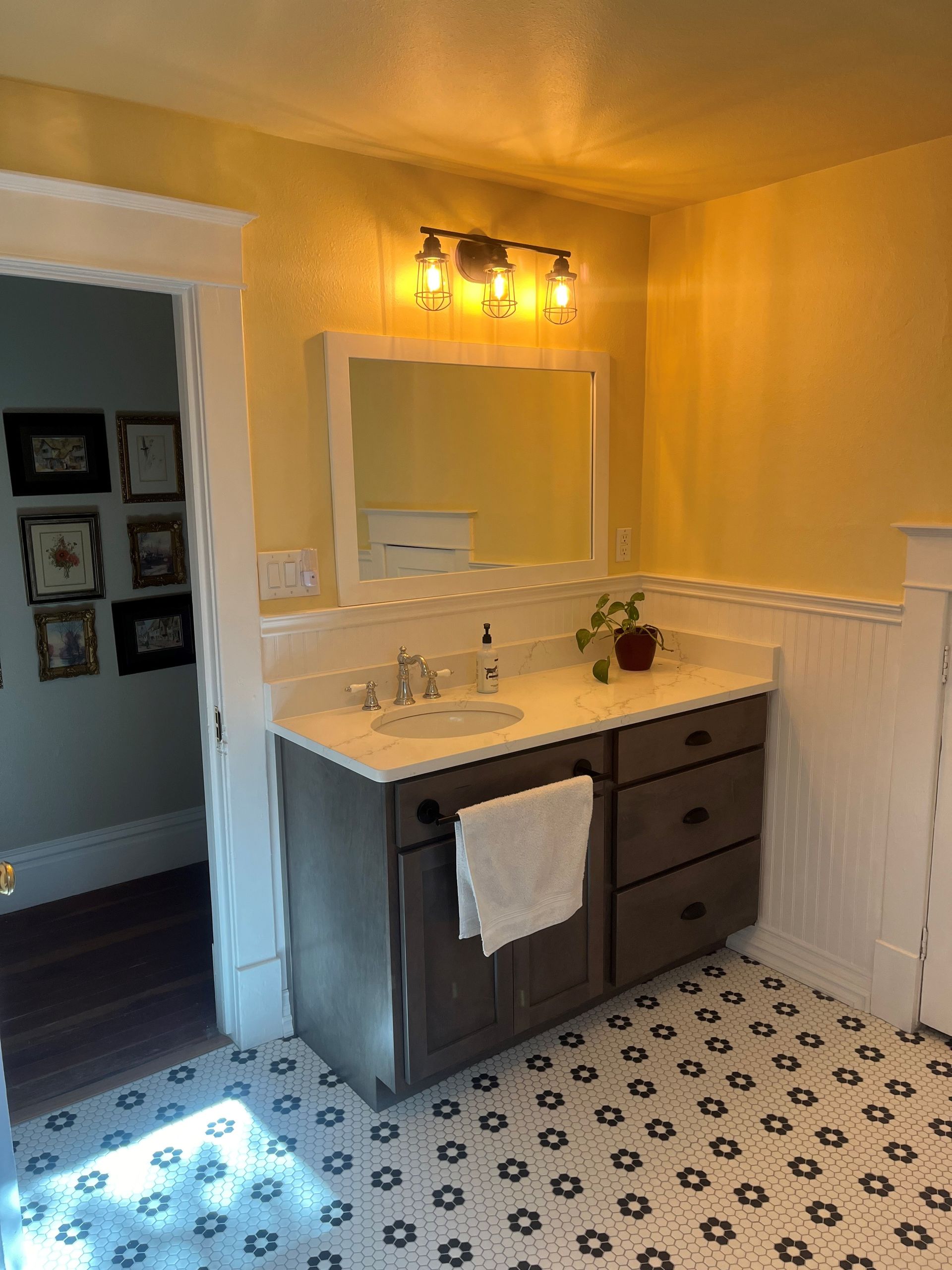 A bathroom with a sink, mirror, and black and white tile floor.