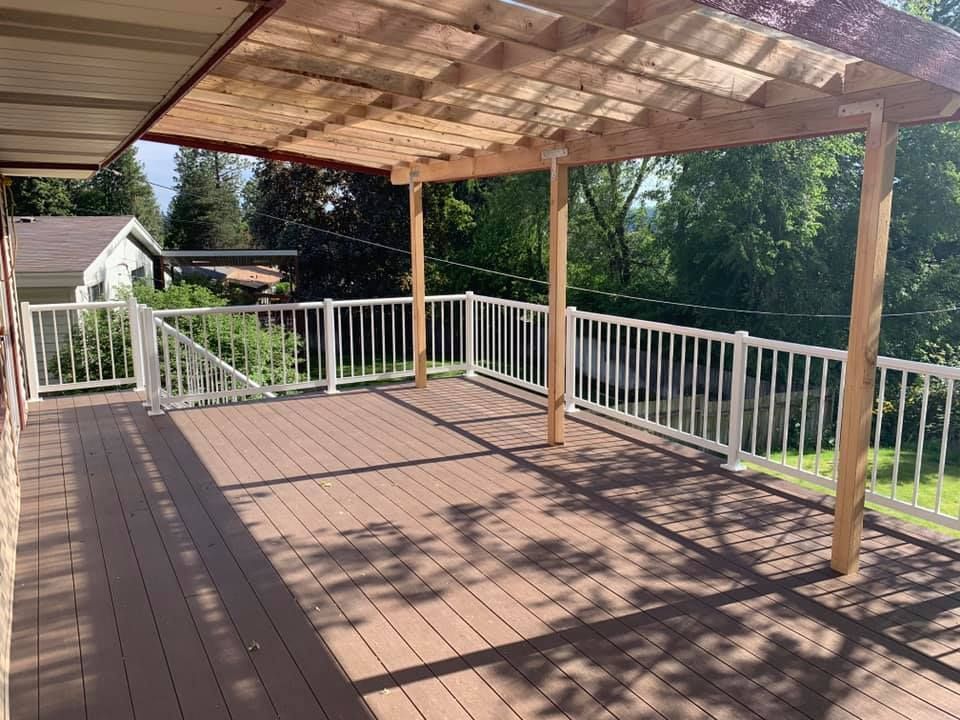 A large deck with a pergola and a white railing.