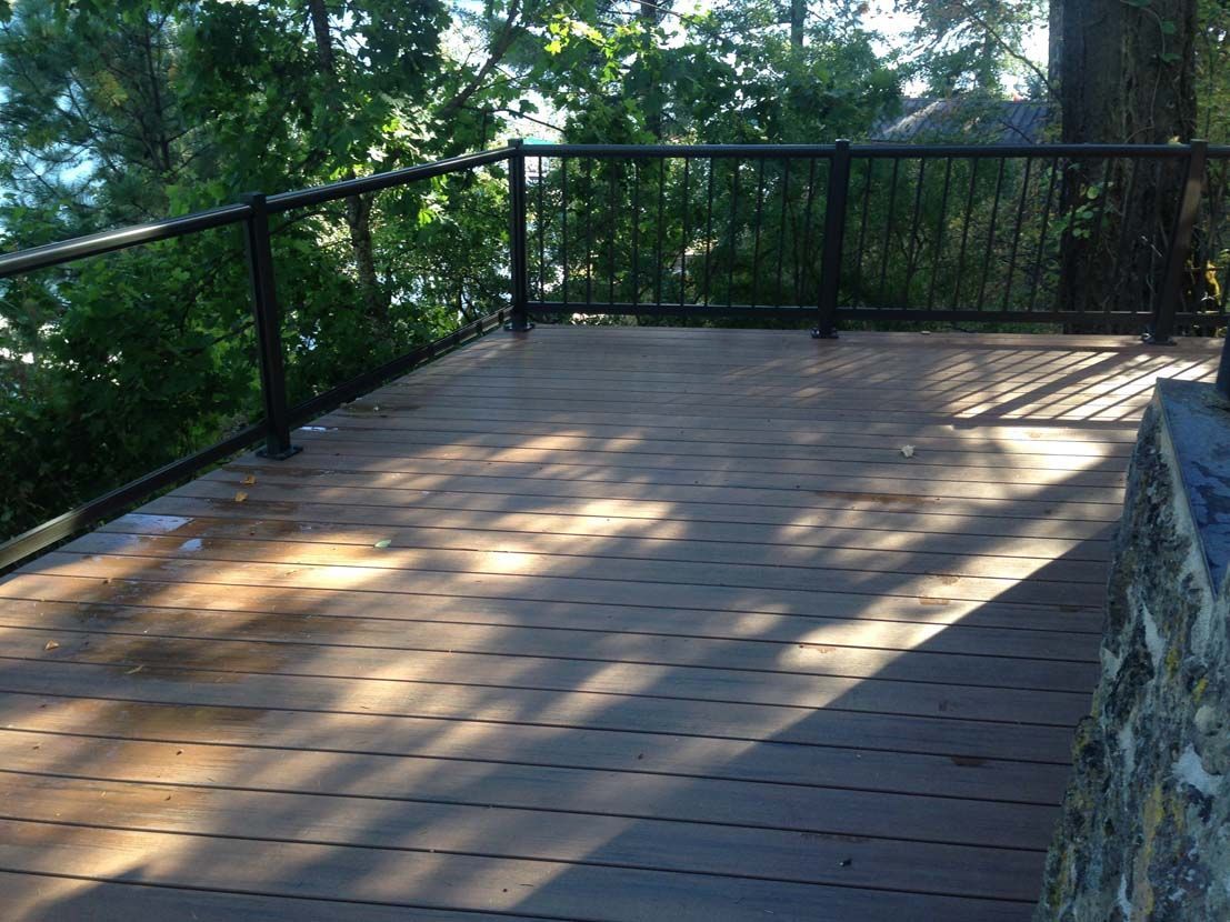 A wooden deck with a metal railing overlooking a body of water.