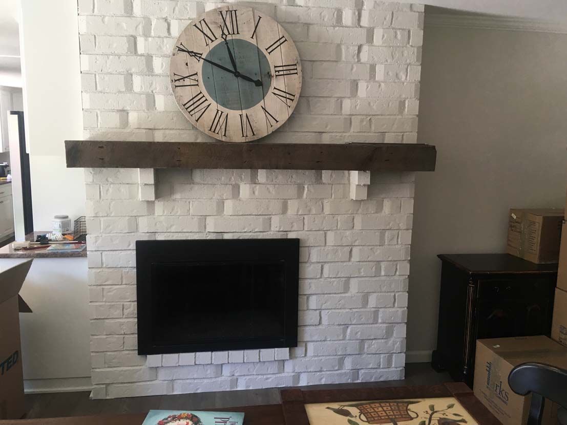 A white brick fireplace with a clock above it.