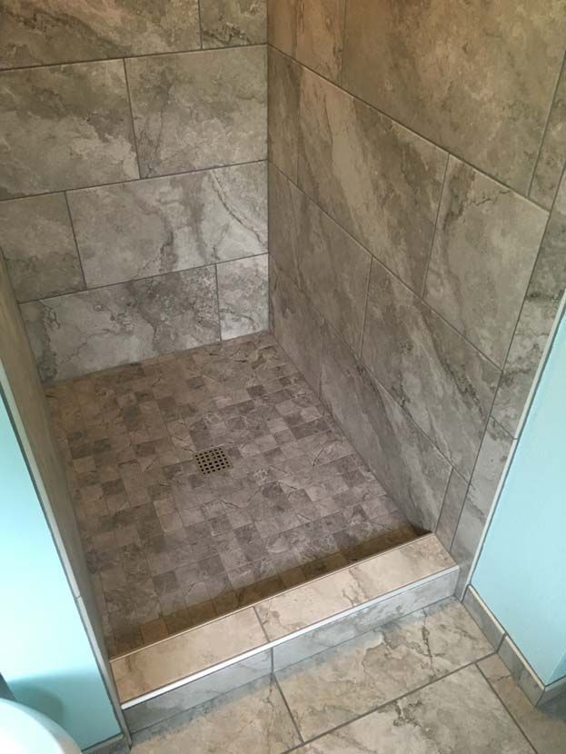 A bathroom with a tiled shower stall and a toilet.