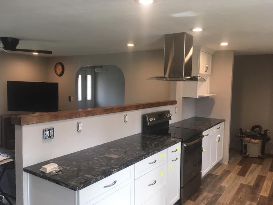 A kitchen with black counter tops and white cabinets and a stove.
