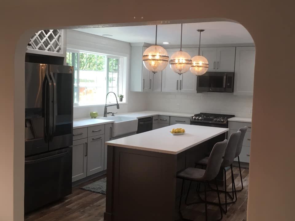A kitchen with white cabinets , black appliances , and a large island.