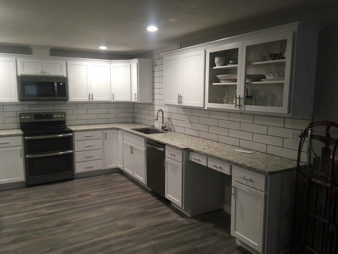 A kitchen with white cabinets , granite counter tops , stainless steel appliances and a stove.