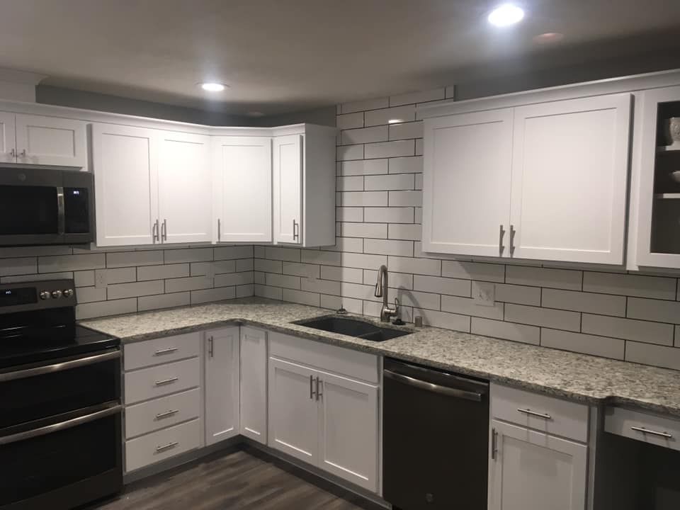 A kitchen with white cabinets , granite counter tops , a stove and a sink.