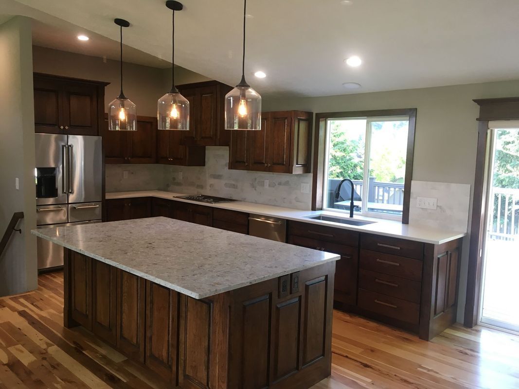A kitchen with wooden cabinets , granite counter tops , stainless steel appliances and a large island.