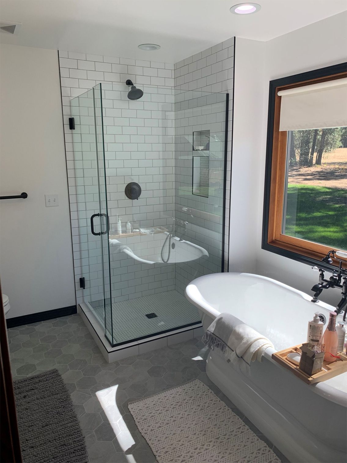 A bathroom with a tub , shower , and window.