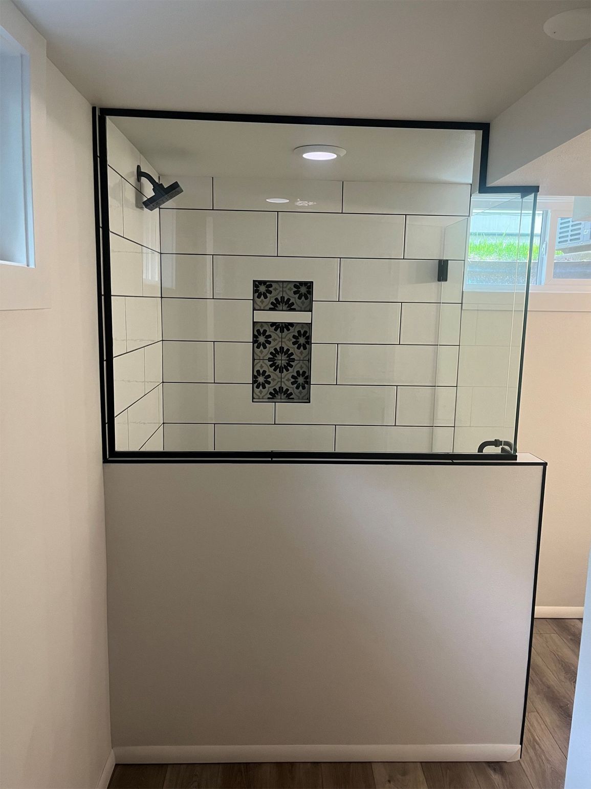 A bathroom with a walk in shower with a glass door.