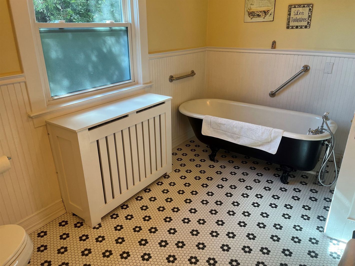 A bathroom with a bathtub, toilet, and window.
