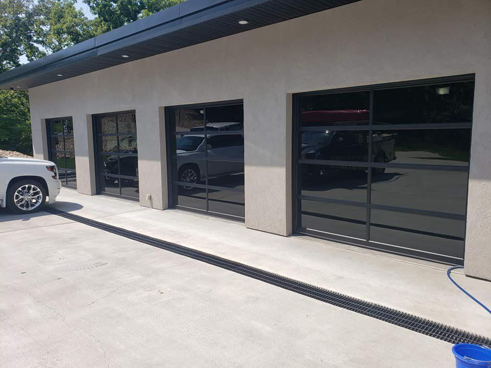 A white suv is parked in front of a garage with a glass door.