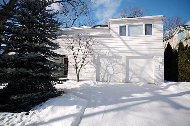A white house with a garage and a driveway covered in snow.