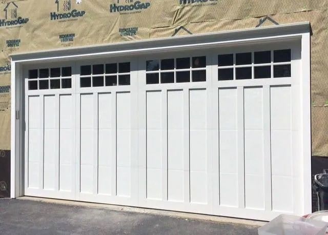 A white garage door is sitting in front of a house that is being built