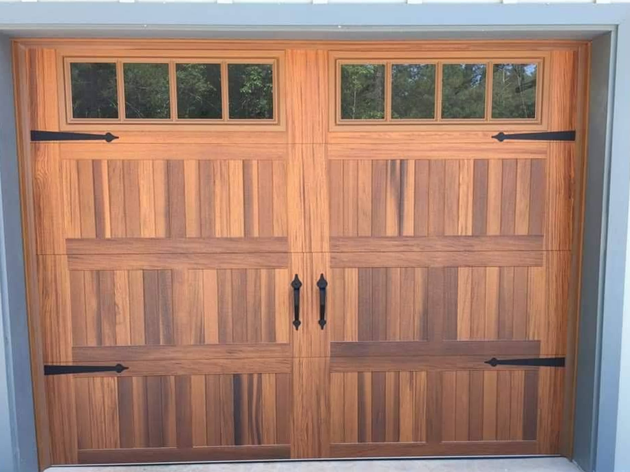 A wooden garage door with black hinges and a window.