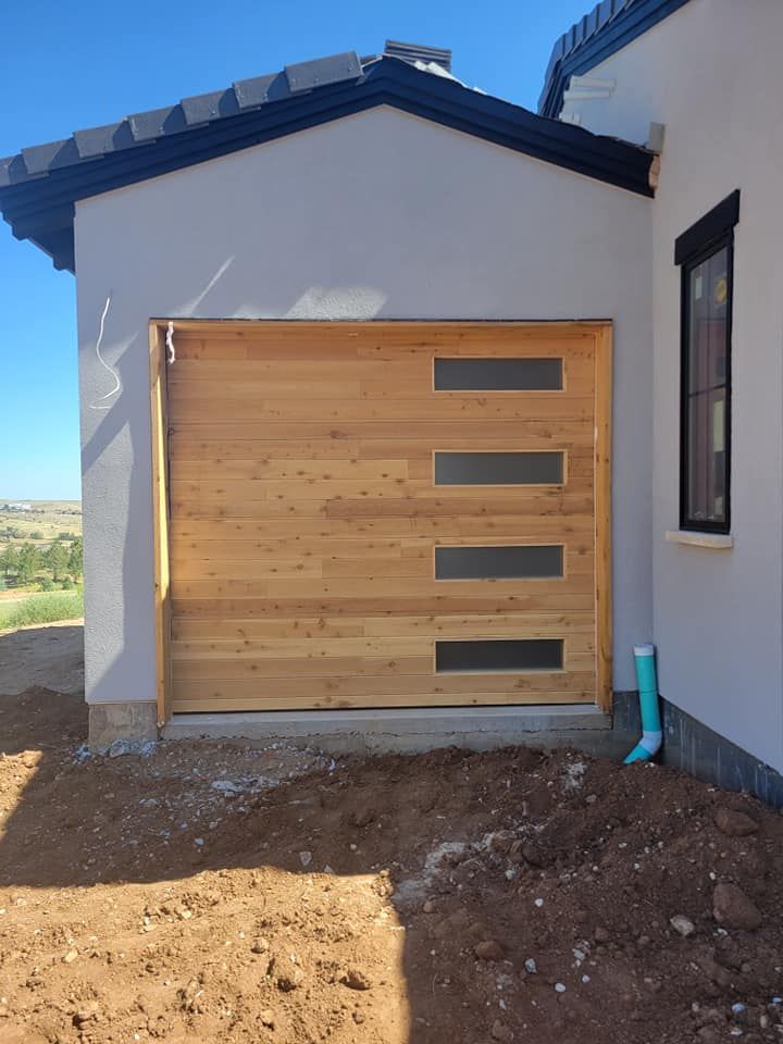 A wooden garage door is sitting in front of a white house.
