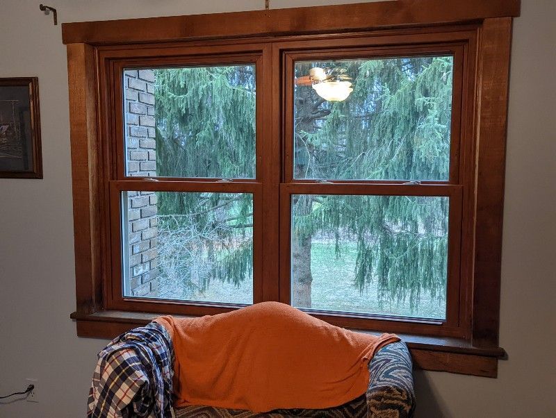 A chair in front of a window with a blanket on it