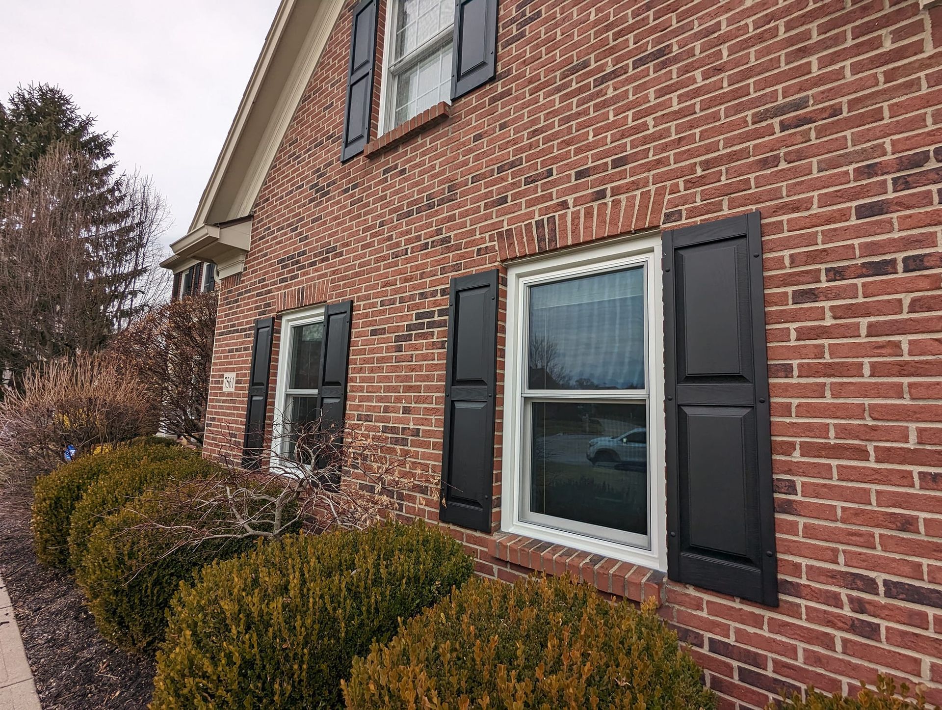 A red brick house with black shutters on the windows.