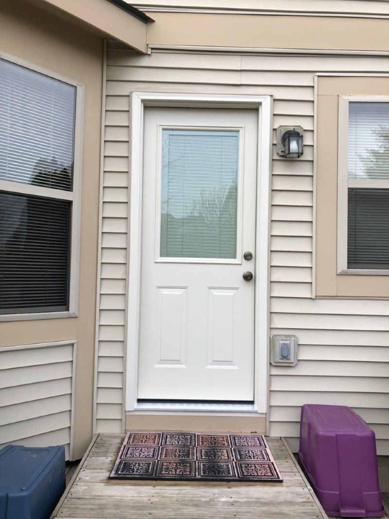 A white door with a window is on the side of a house.
